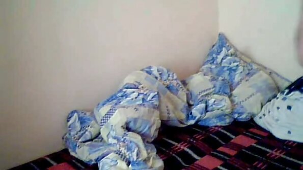 Seekor jalang berambut hitam berada di atas sofa, menjilat ereksi yang besar